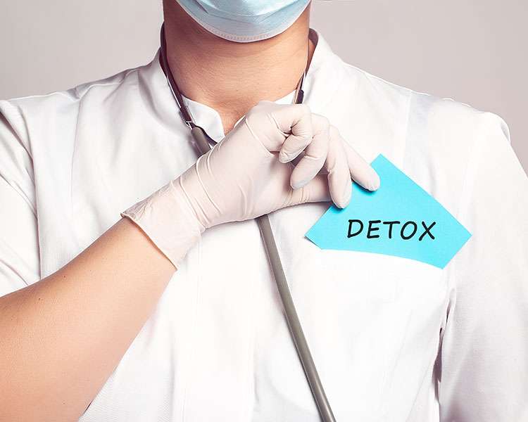 Nurse holding a sticky note that says Detox