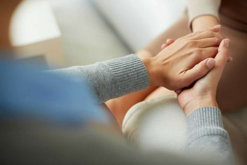 People holding hands in a supportive way.