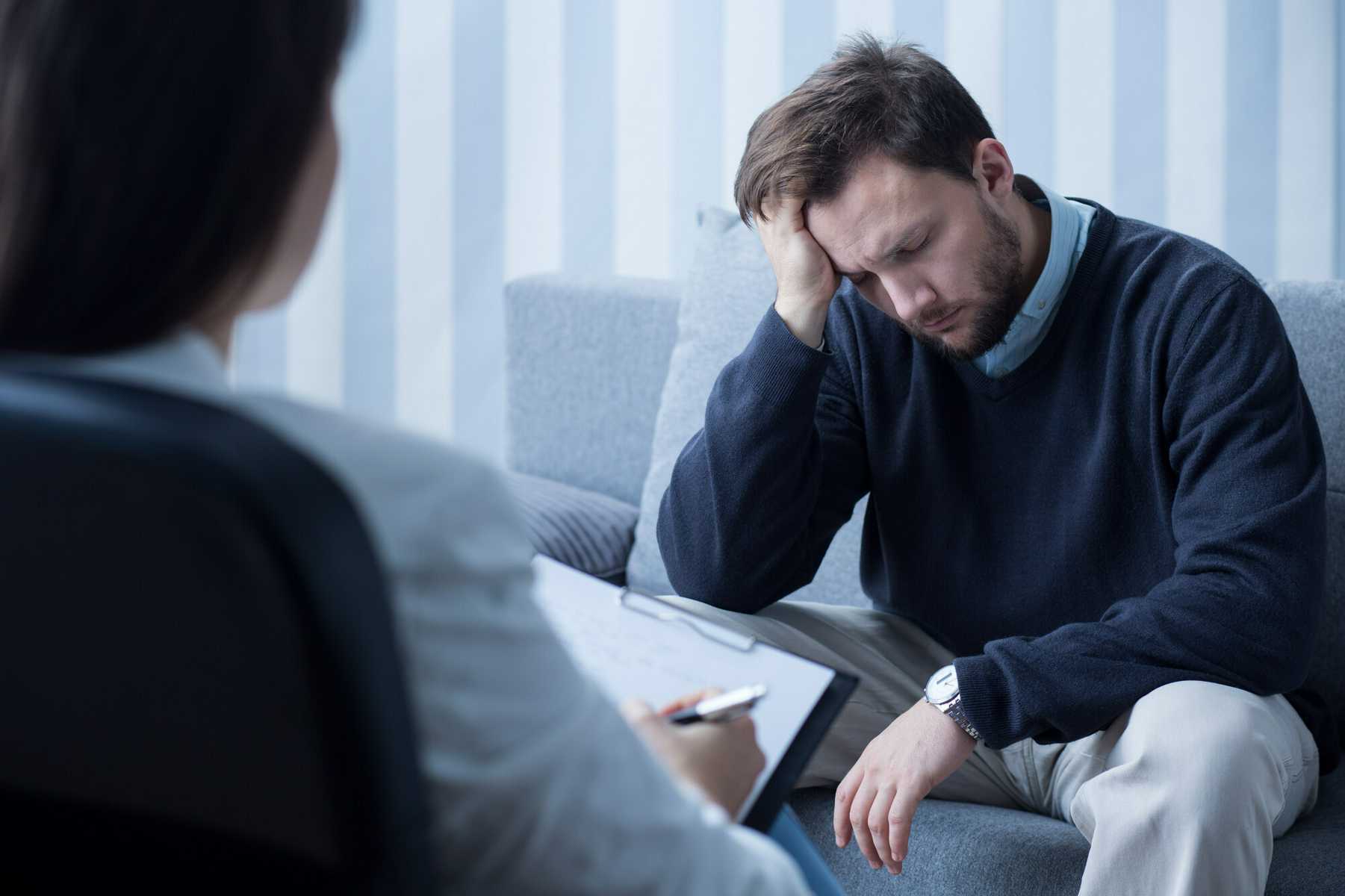 Depressed man sitting during therapy session for alcohol addiction