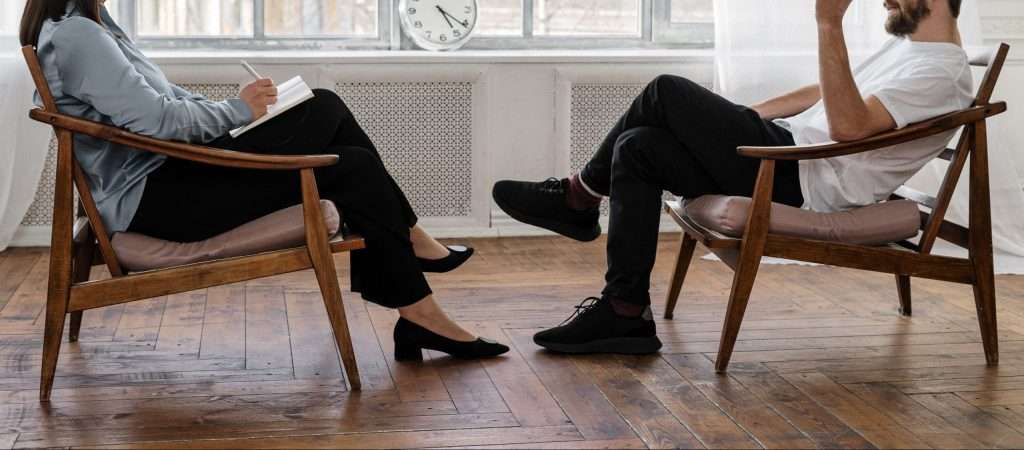 Two people sitting facing each other during a counselling session.