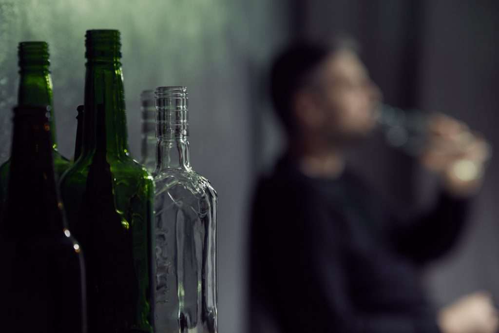 Person sitting on the ground drinking out of a large alcohol bottle, Alcohol Rehab Toronto, Alcohol Treatment Toronto, Alcohol Rehab Ontario, Alcohol Treatment Ontario