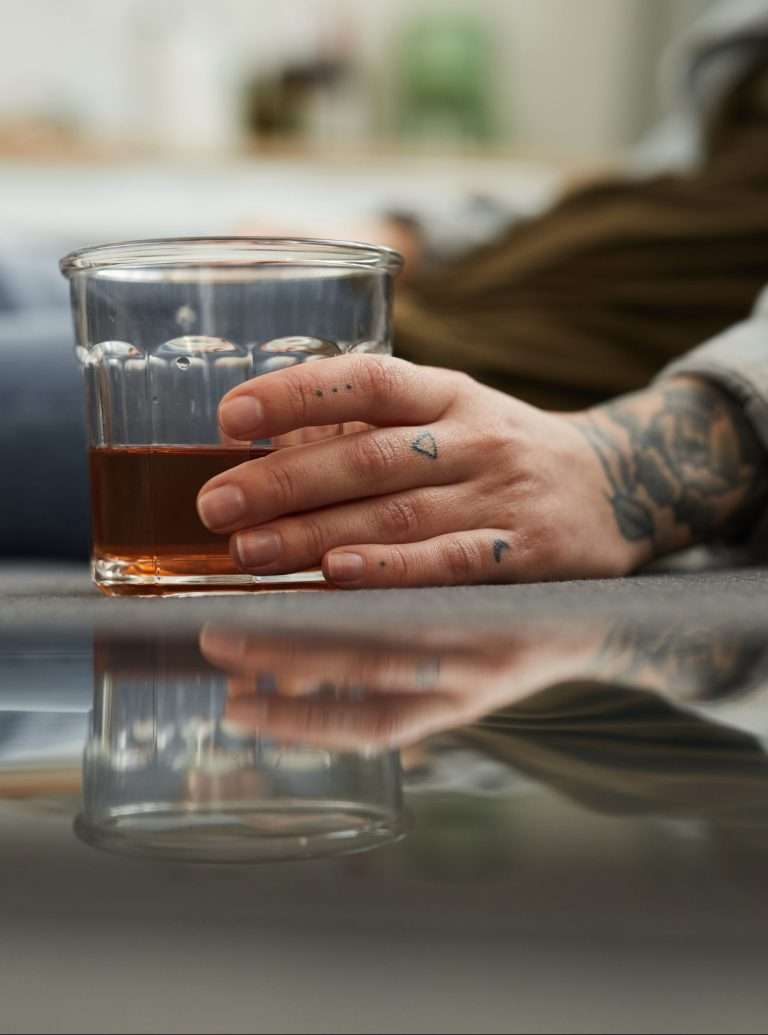 Persons hand holding a glass of alcohol while they're sitting on the floor, Alcohol Rehab Toronto, Alcohol Treatment Toronto, Alcohol Rehab Ontario, Alcohol Treatment Ontario