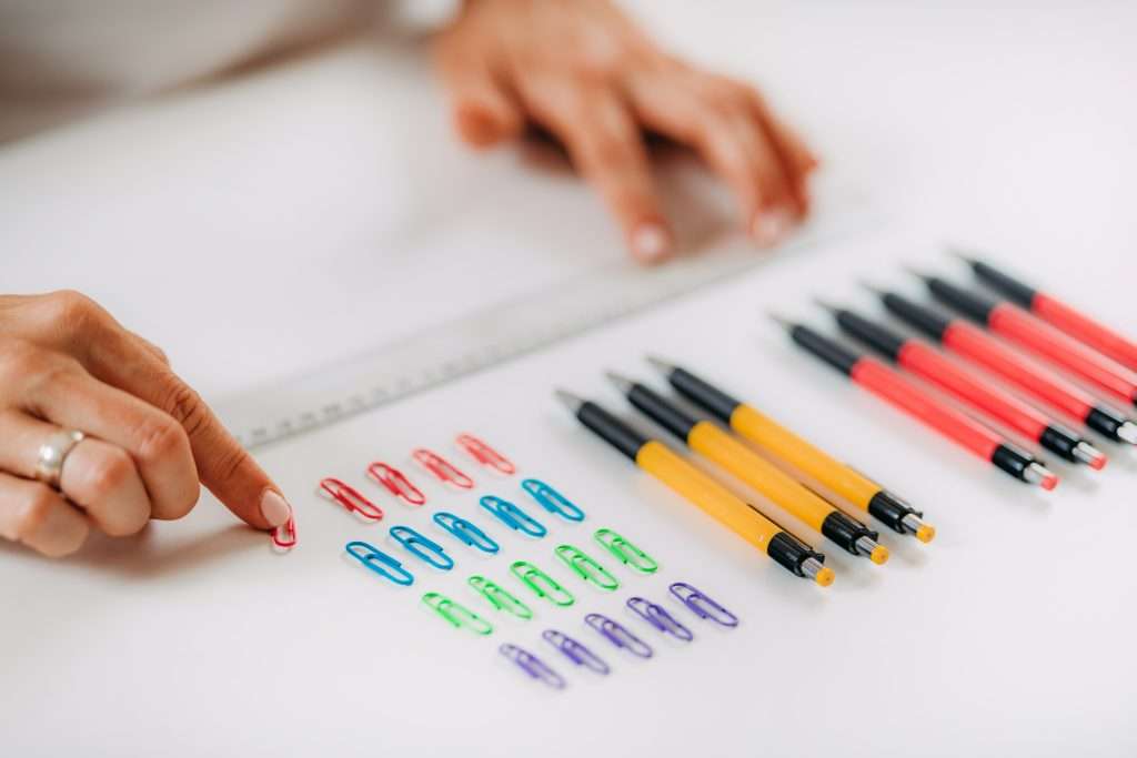 Woman with OCD – Obsessive compulsive disorder concept. Placing paperclips in a straight line.